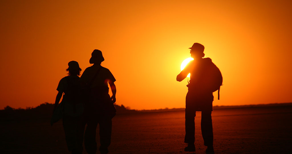 Okavango Expeditions guests silhouetted against the sunset